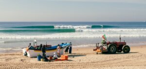 In Lissabon surfen - Surfer und Fischer an einem Beachbreak an der Costa da Caparica