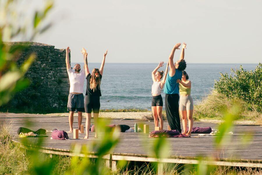 Yogalehrerin Nina vom Goodtimes Portugal Surf- und Yogacamp korrigiert die Haltung in einer der Asanas