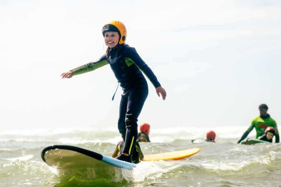 Kind mit Helm im Surfkurs von Tres Ondas in Ericeira Portugal
